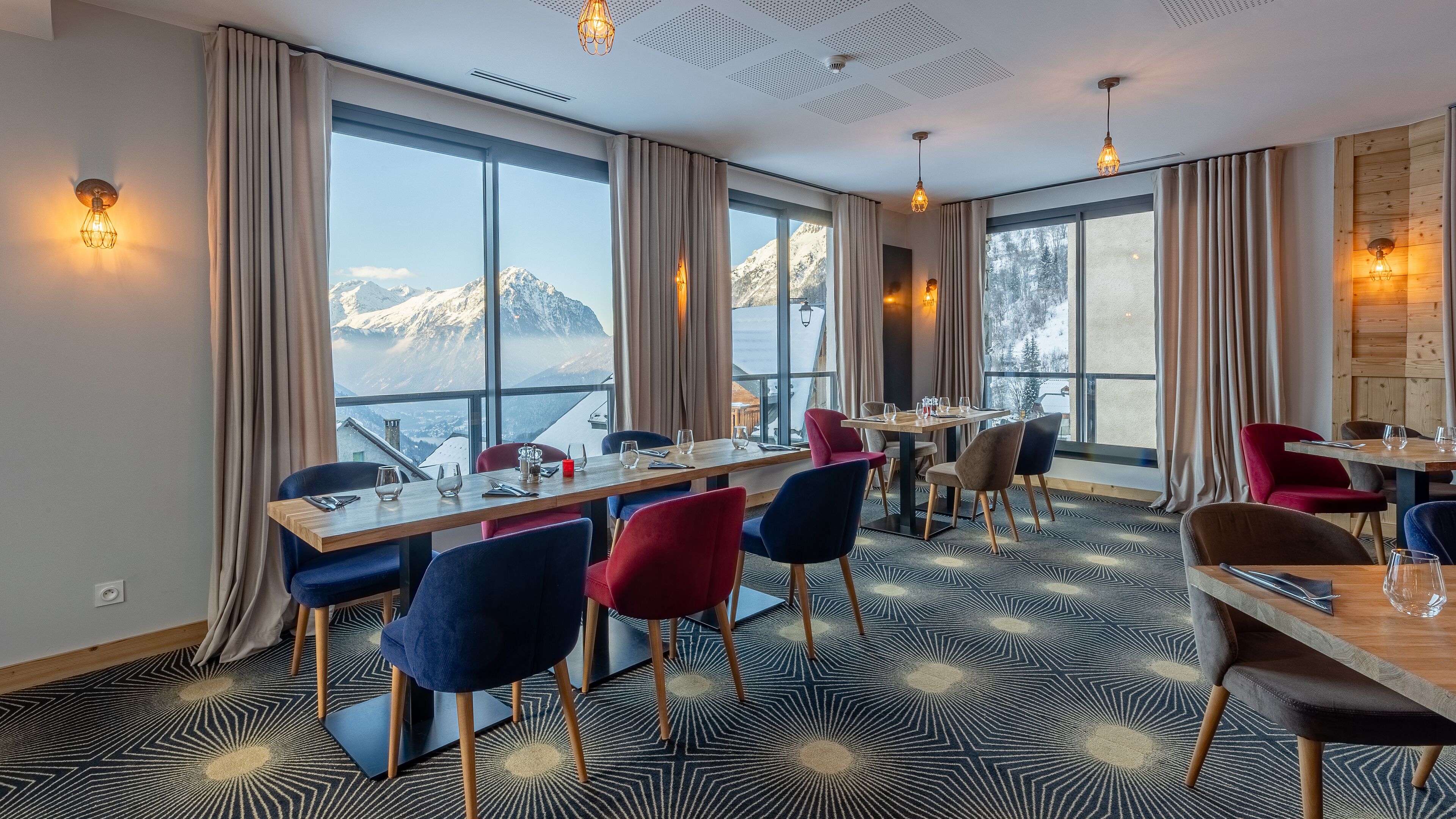 A dining area with a mountain view, large windows, and modern decor.