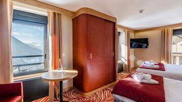 Habitación de hotel con cama, una mesita, televisión y vistas a montañas.