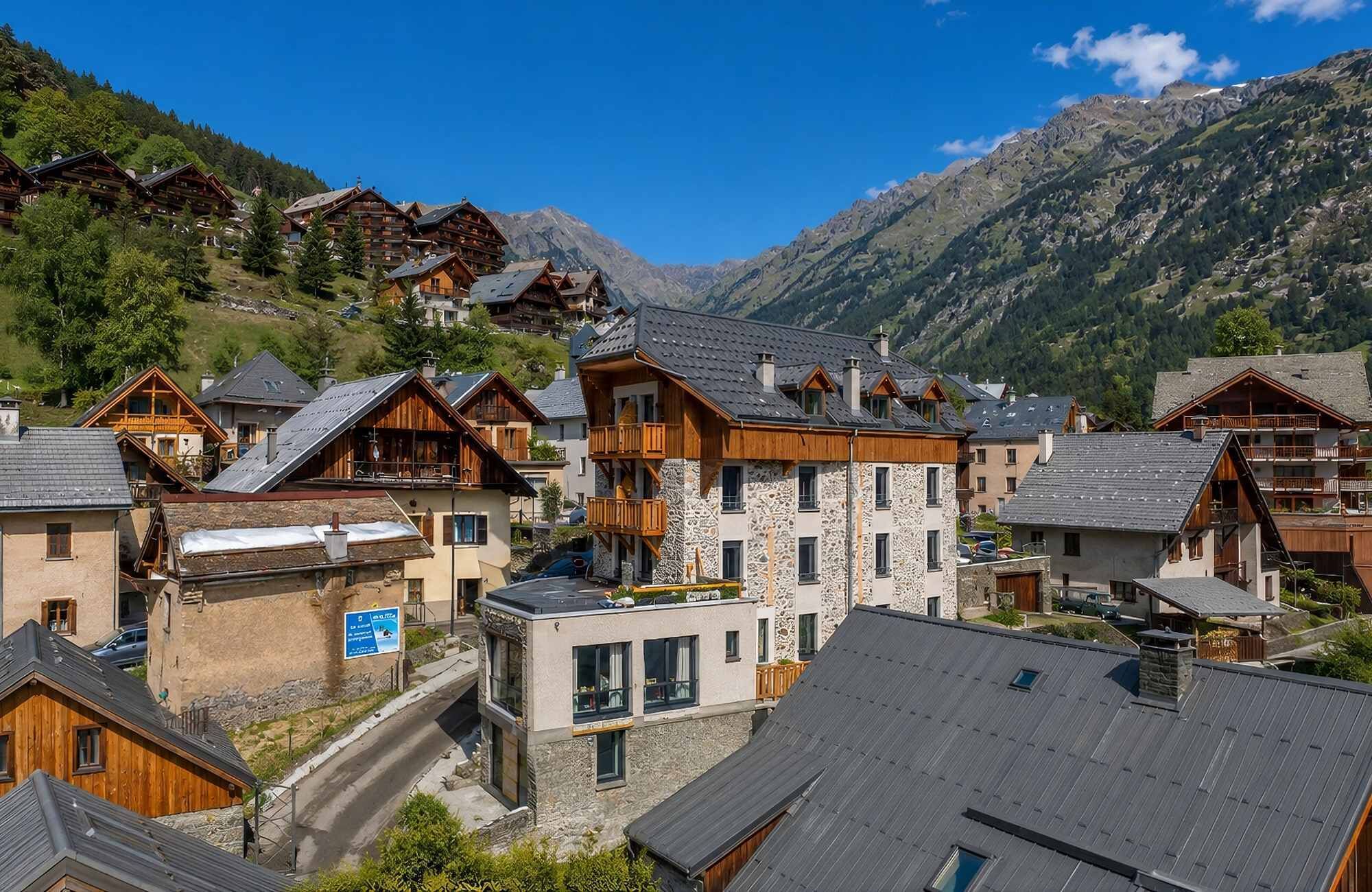 Un pueblo de montaña con edificios de madera tradicionales, fachadas de piedra y una vista despejada de las montañas circundantes.