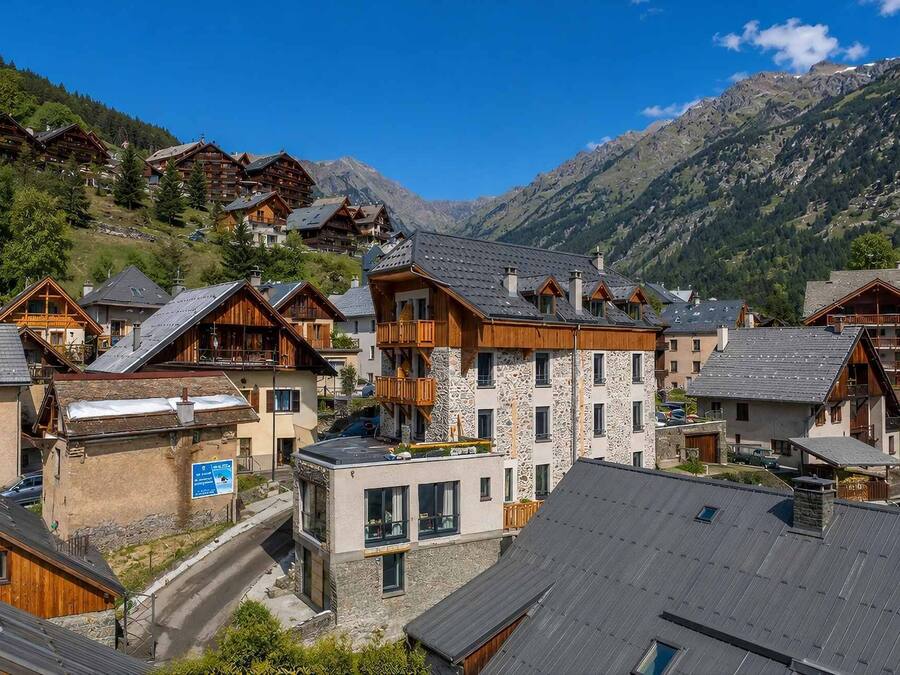A mountain village with traditional wooden buildings, stone facades, and a clear view of the surrounding mountains.