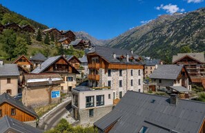 A mountain village with traditional wooden buildings, stone facades, and a clear view of the surrounding mountains. - Madame Vacances Hôtel les Cimes (Vaujany)