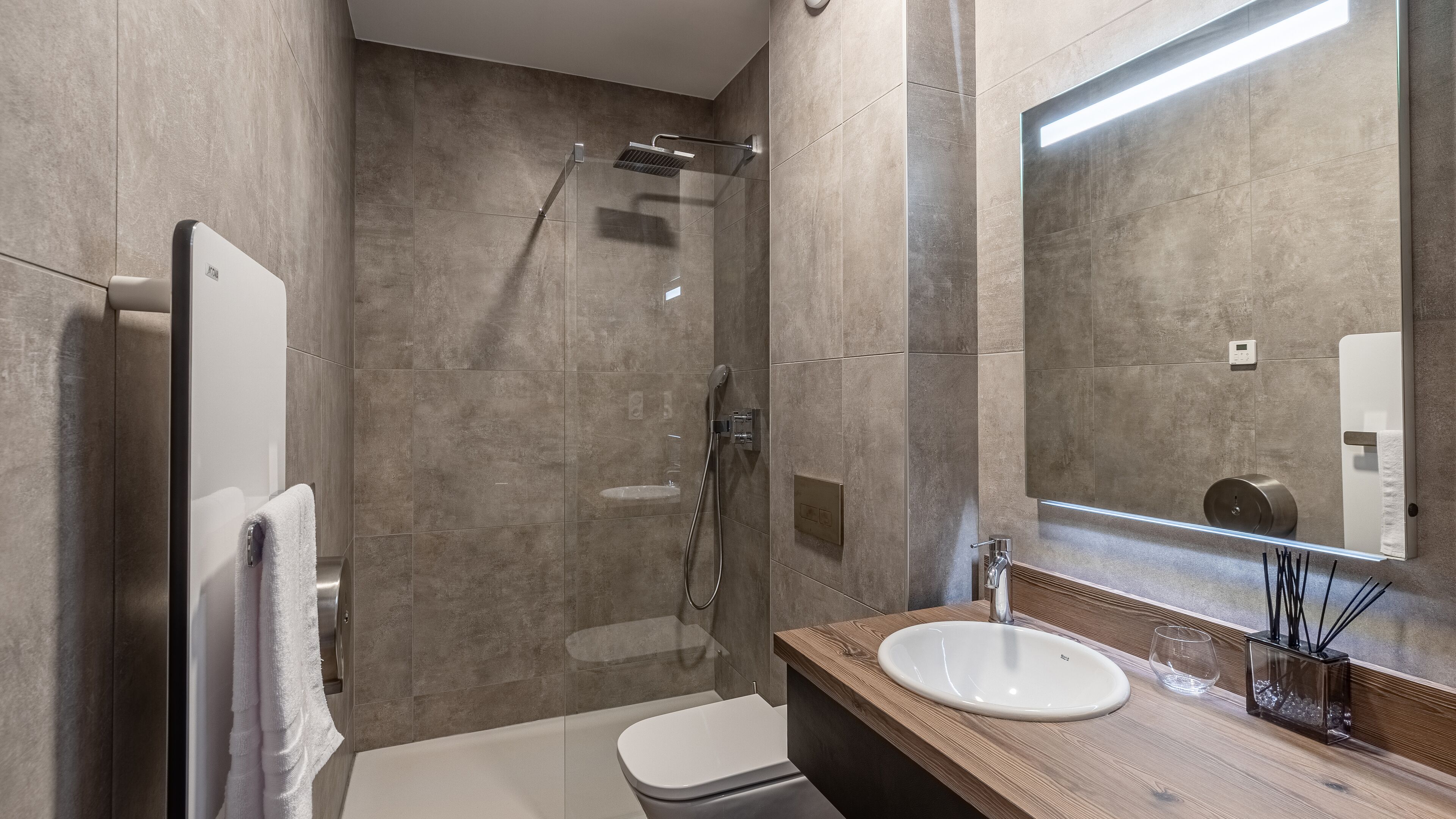 Un bagno moderno con doccia a filo pavimento, un water e un lavabo con piano in legno.