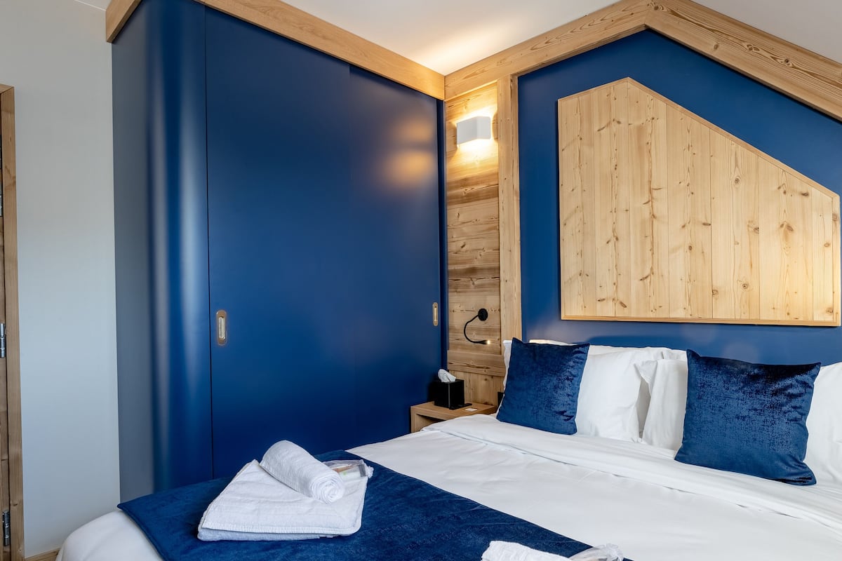 Ein Schlafzimmer mit einem großen Bett, einem Holzkopfende und einer blauen Akzentwand.