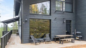 Uma casa moderna com terraço, janelas amplas e mobiliário para área externa.