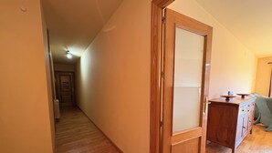 Un pasillo con piso de madera, una puerta de madera y un aparador con cajones.