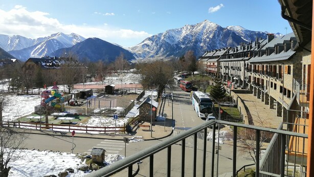Un pueblo de montaña con picos nevados, un parque infantil y una hilera de edificios tradicionales.