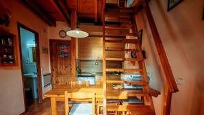 Eine Holztreppe führt zu einer Küche mit Esstisch und Stühlen.