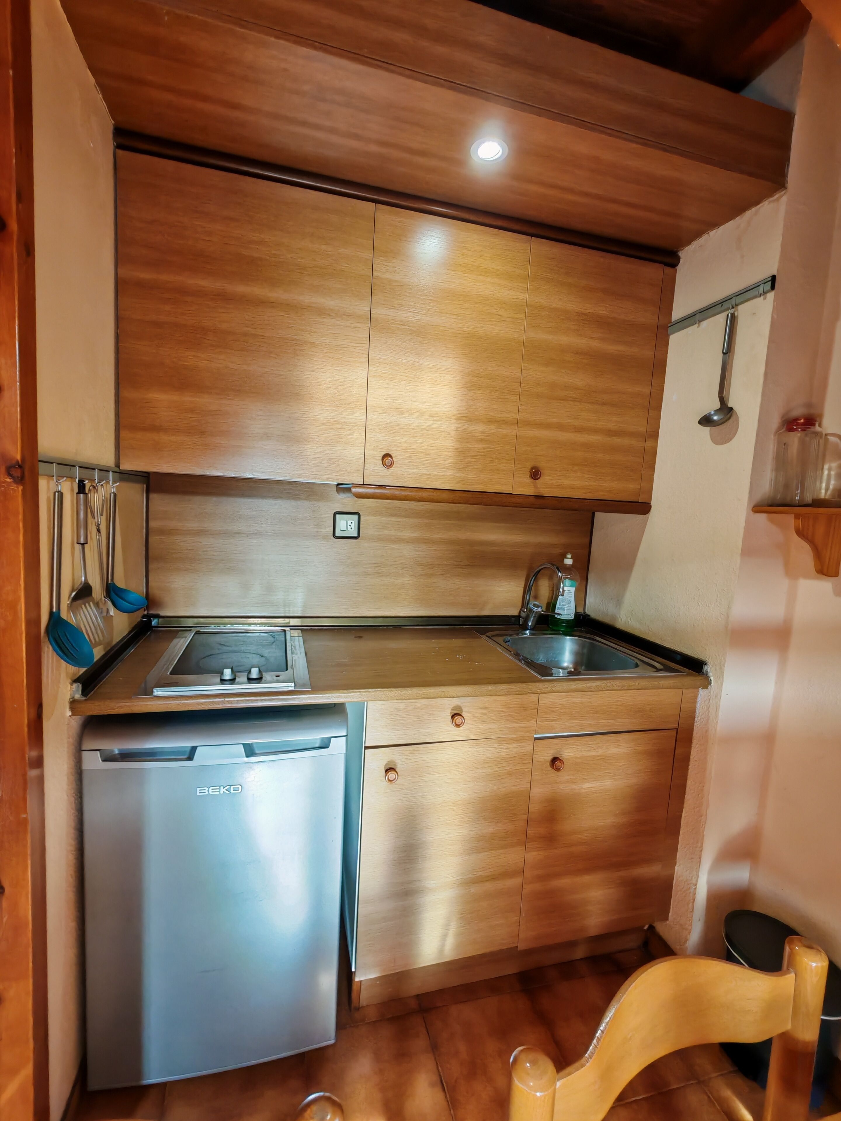 A compact kitchen with wooden cabinets, a built-in dishwasher, and a sink.