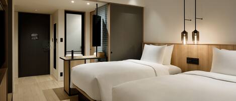 A modern hotel room with two beds, a wooden headboard, a bedside table, a mirror, and a hanging light fixture.