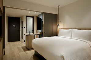 Ein modernes Hotelzimmer mit einem großen Bett, einem Nachttisch, einem Spiegel und einer kleinen Schreibtischzeile.