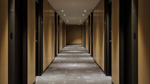 Un long couloir étroit aux murs et aux portes en bois, qui mène à plusieurs pièces.