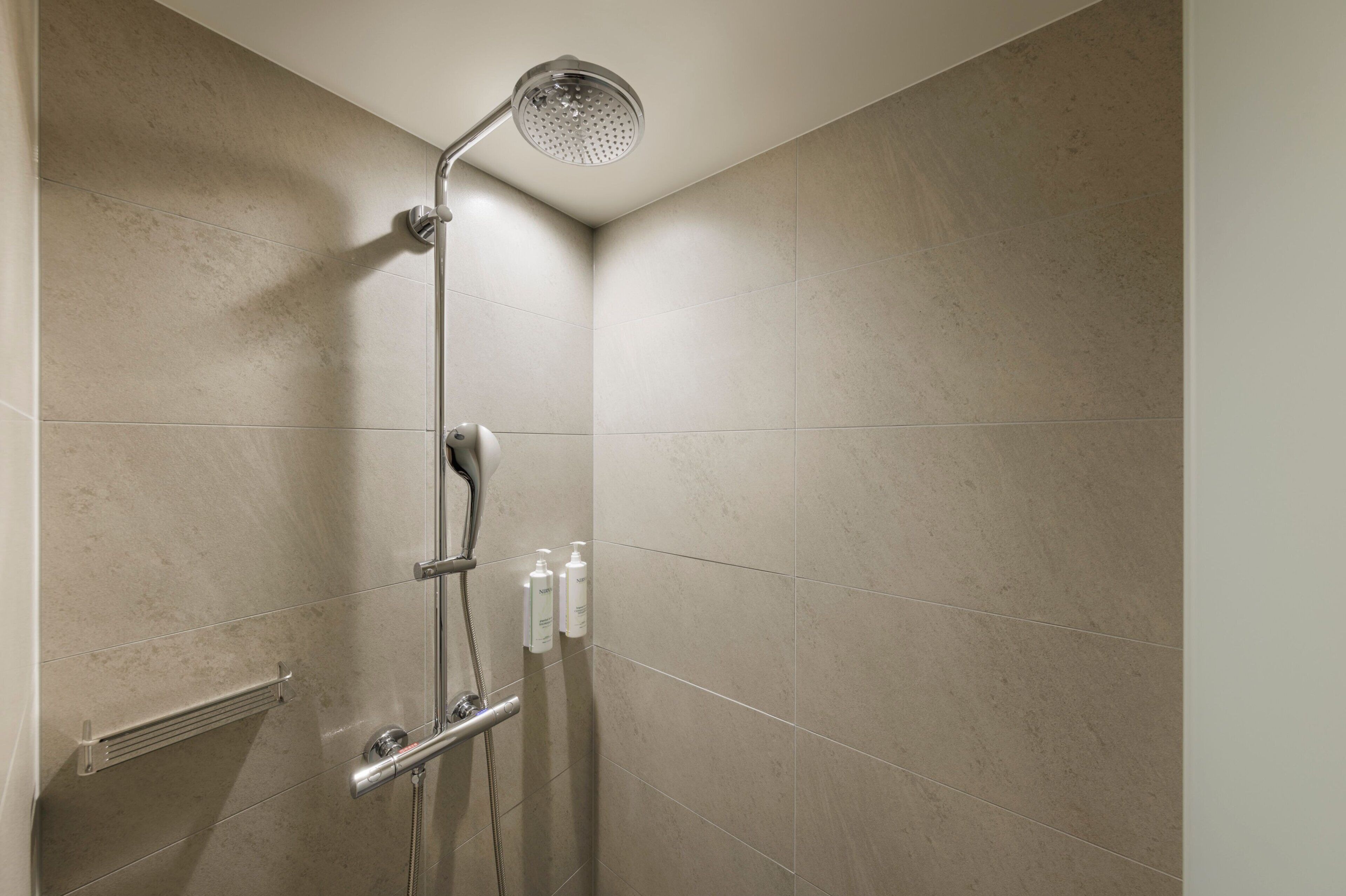 A modern shower with a handheld showerhead, a handheld shower attachment, and a handheld shower head.