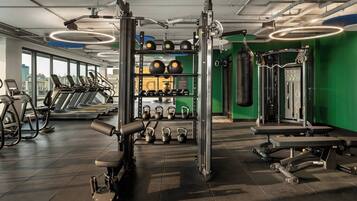 Una palestra con tapis roulant, macchinari per pesi, kettlebell e un sacco da boxe.
