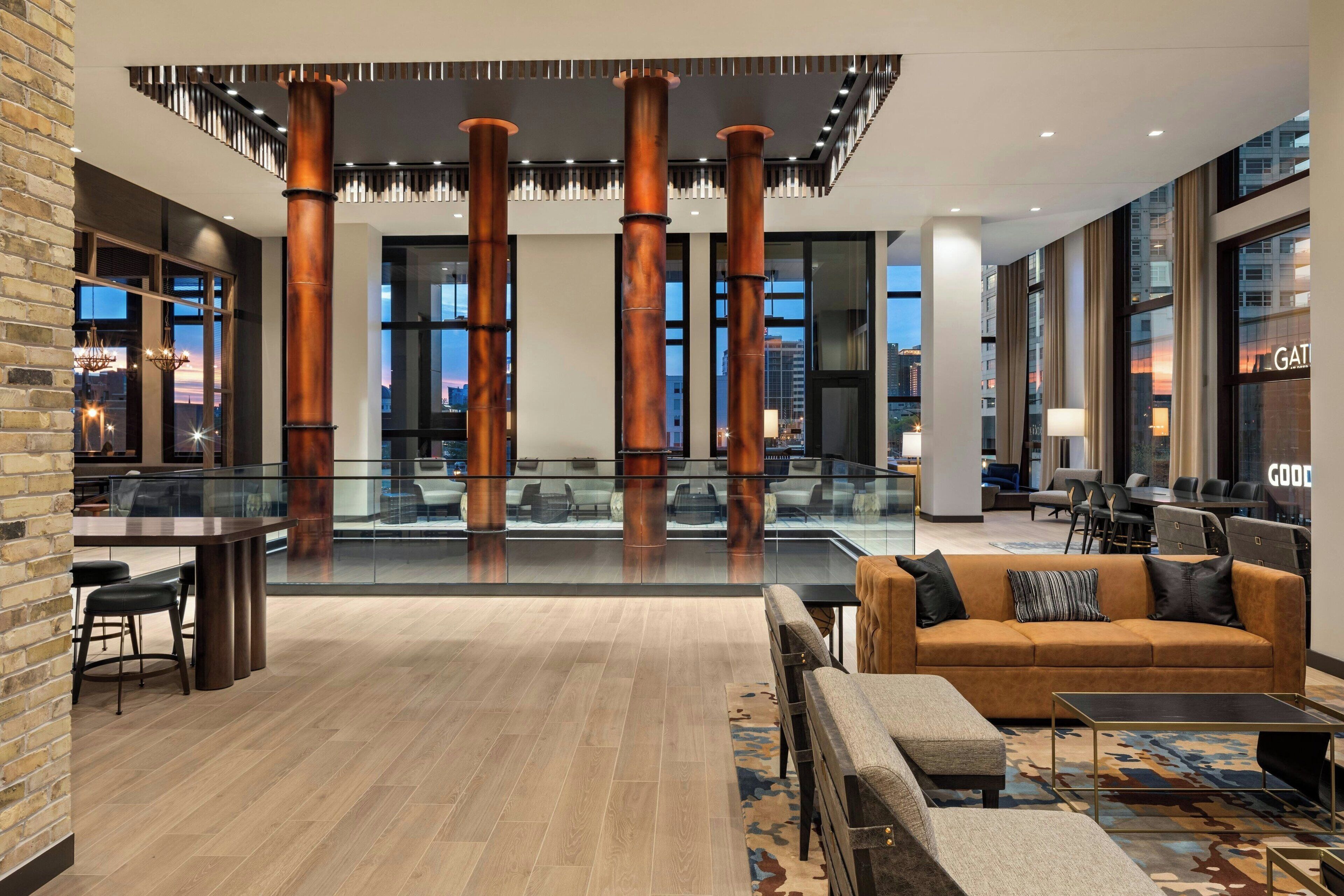 A spacious lobby with a modern design, featuring a central seating area with a sofa and chairs, a glass coffee table, and a patterned rug.