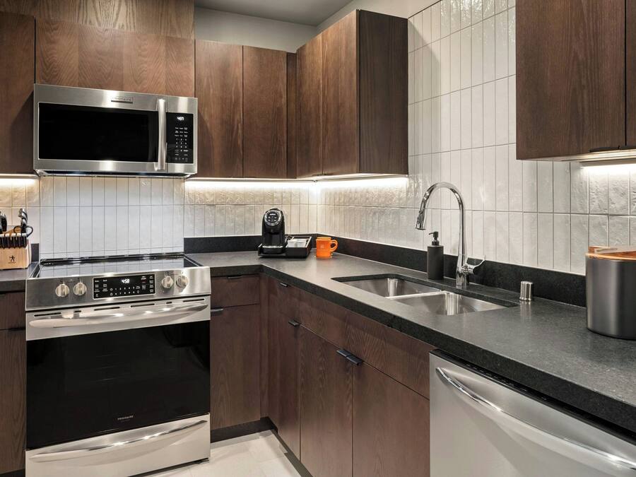 A modern kitchen with stainless steel appliances, wooden cabinets, and a black countertop.