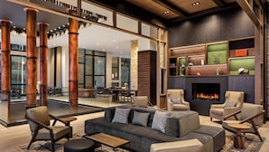 A modern lobby with a large seating area, a fireplace, and a view of the dining area. - The Trade, Autograph Collection (Milwaukee)