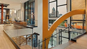 A spacious lobby with a glass railing, a staircase, and a view of the cityscape. - The Trade, Autograph Collection (Milwaukee)
