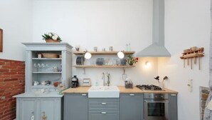 A kitchen with grey cabinets, a wooden countertop, a gas stove, and a built-in oven. There are shelves above the countertop holding dishes and a hanging rack on the wall. - CASA AMELIE - APARTMENT IN FLORENCE FREE WIFI + ETHERNET (Firenze)