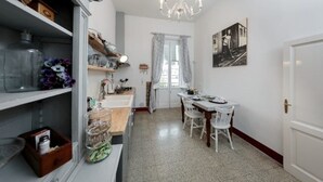A kitchen with a dining area, featuring a chandelier, a dining table with chairs, and a window with curtains. - CASA AMELIE - APARTMENT IN FLORENCE FREE WIFI + ETHERNET (Firenze)