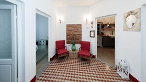 A hallway with two red chairs, a patterned floor, a brick accent wall, and a kitchen in the background. - CASA AMELIE - APARTMENT IN FLORENCE FREE WIFI + ETHERNET (Firenze)