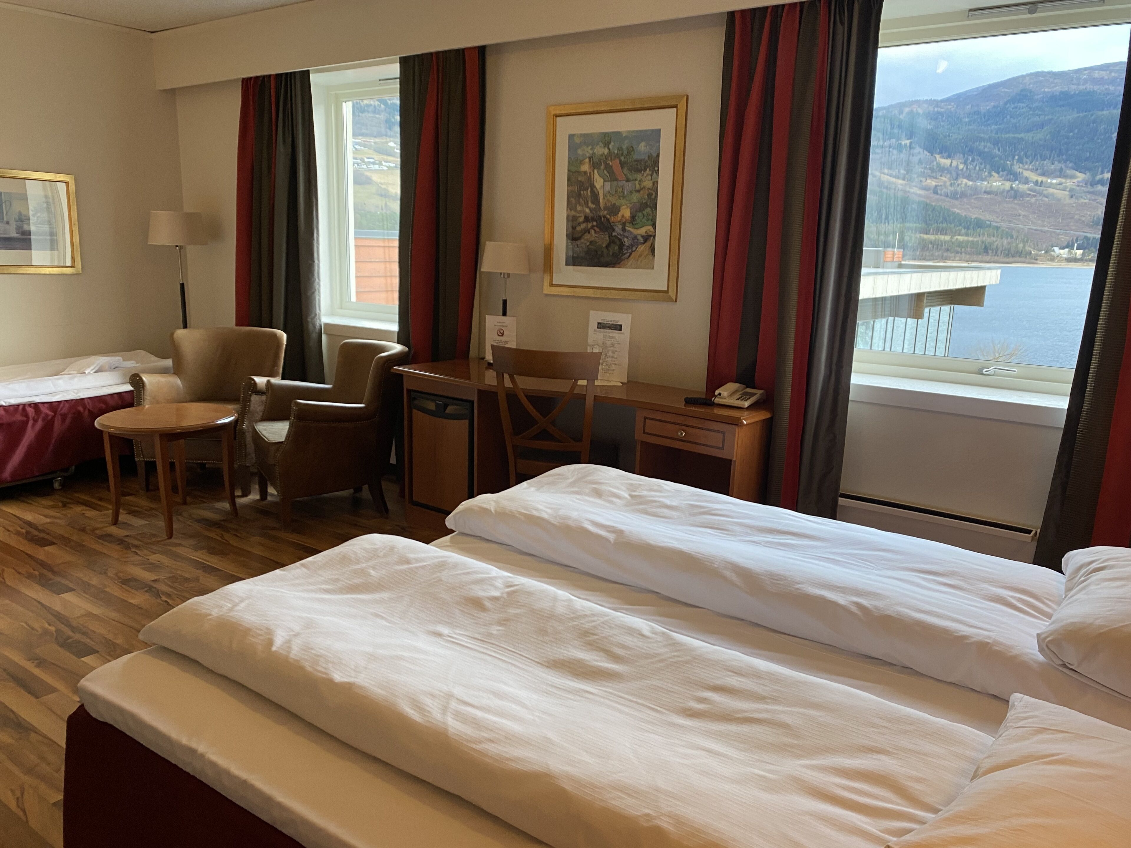 Une chambre d’hôtel avec un lit, un bureau, une chaise et une vue sur la mer.