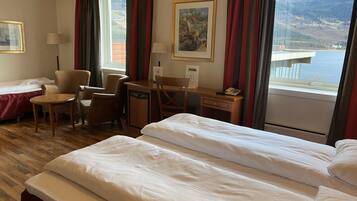Une chambre d’hôtel avec un lit, un bureau, une chaise et une vue sur la mer.