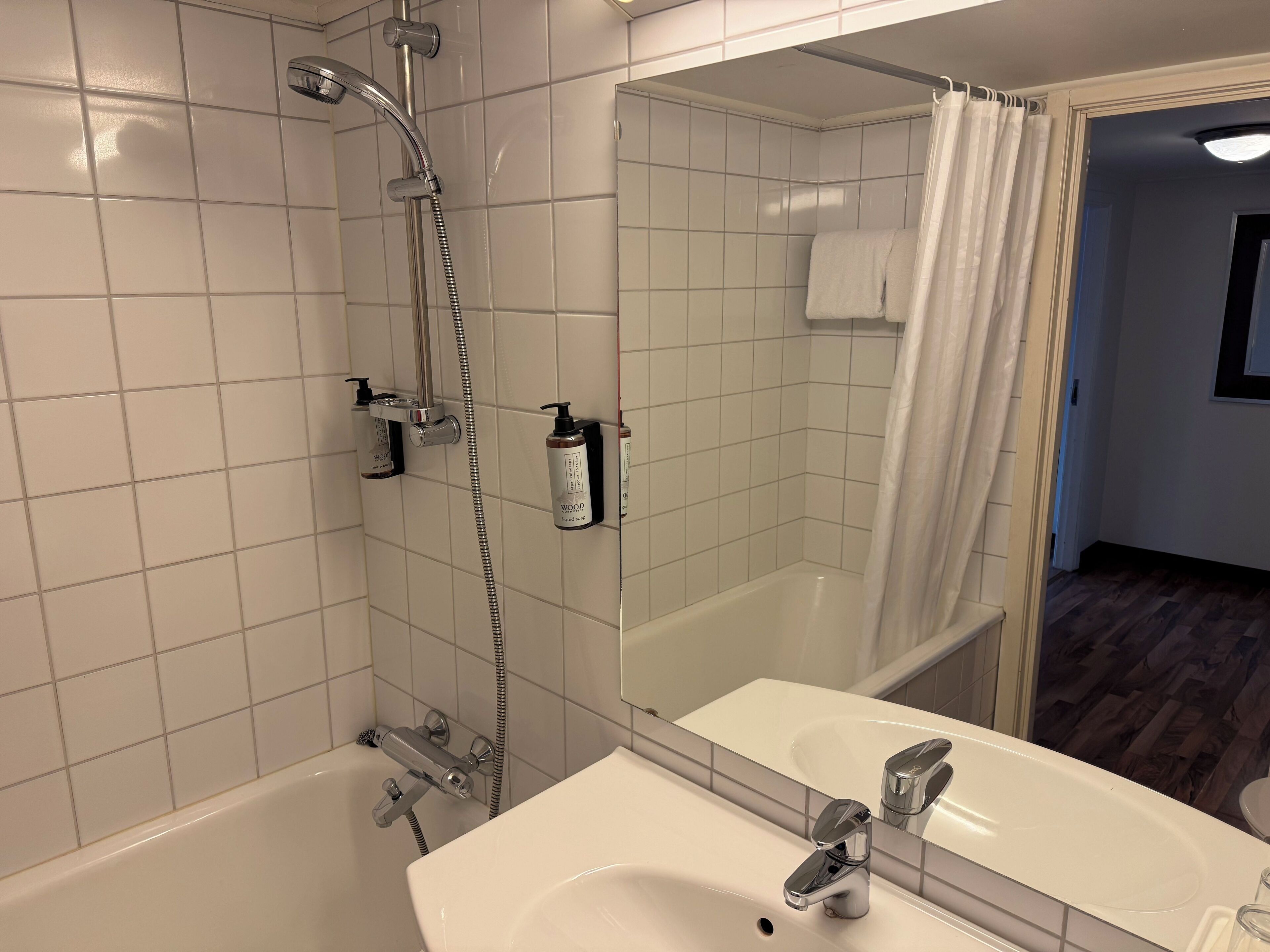 A bathroom with a bathtub, a shower, a sink, and a mirror.