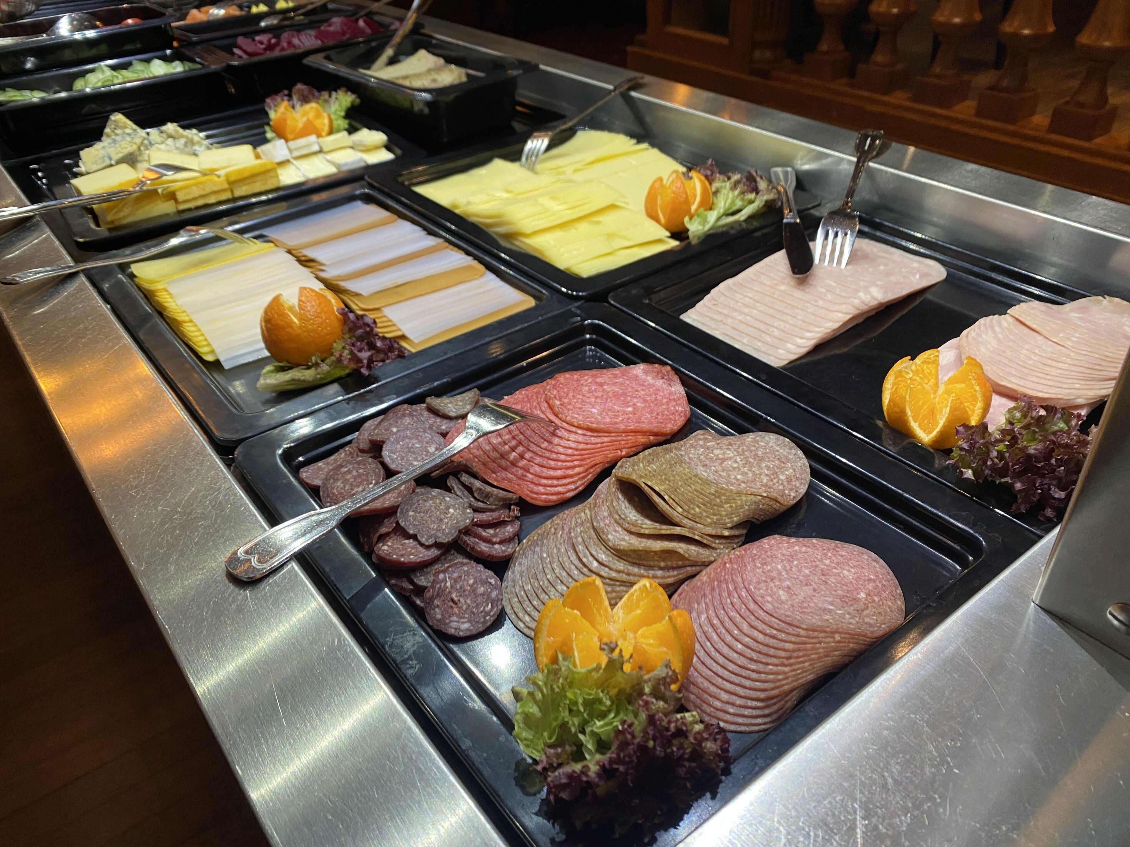 A buffet with various food items including meats, cheeses, and fruits.