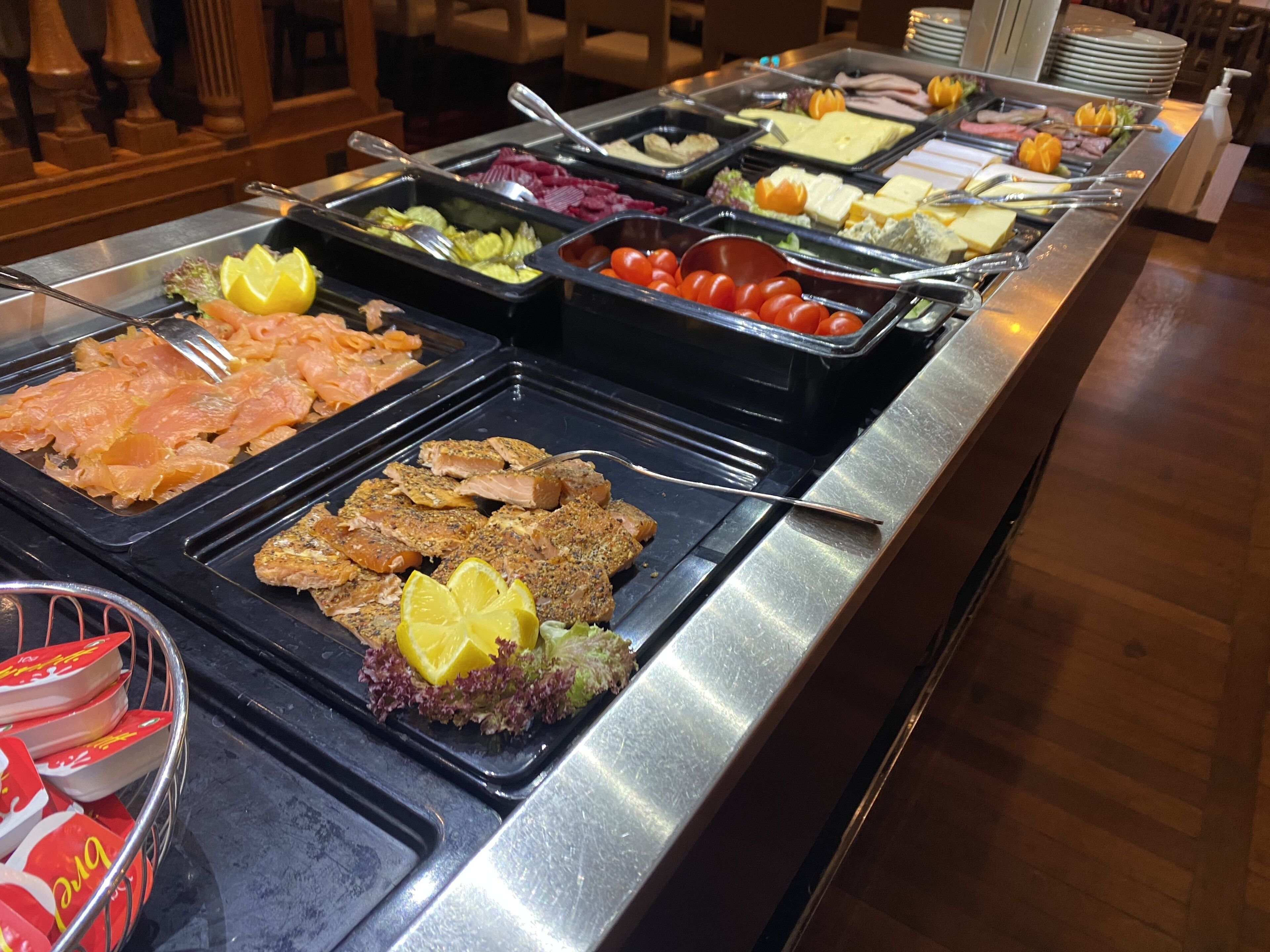 A buffet with various food options including salmon, salads, and other dishes.