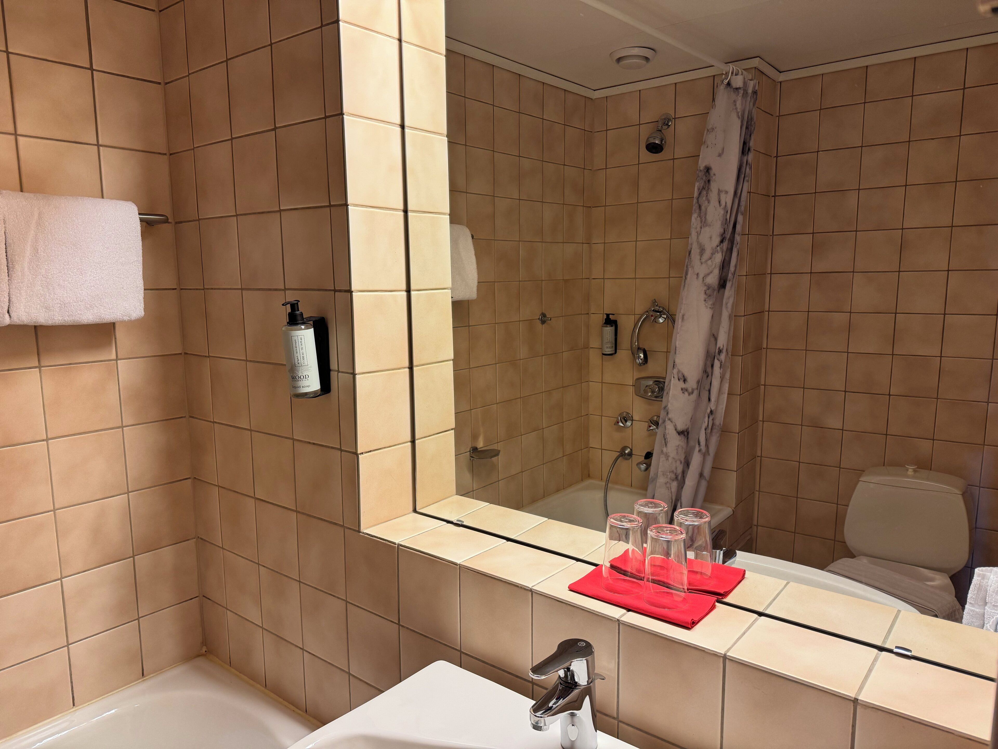 Un baño con bañera, lavamanos, espejo y ducha.