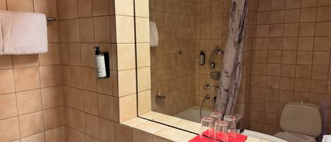 Un baño con bañera, lavamanos, espejo y ducha.