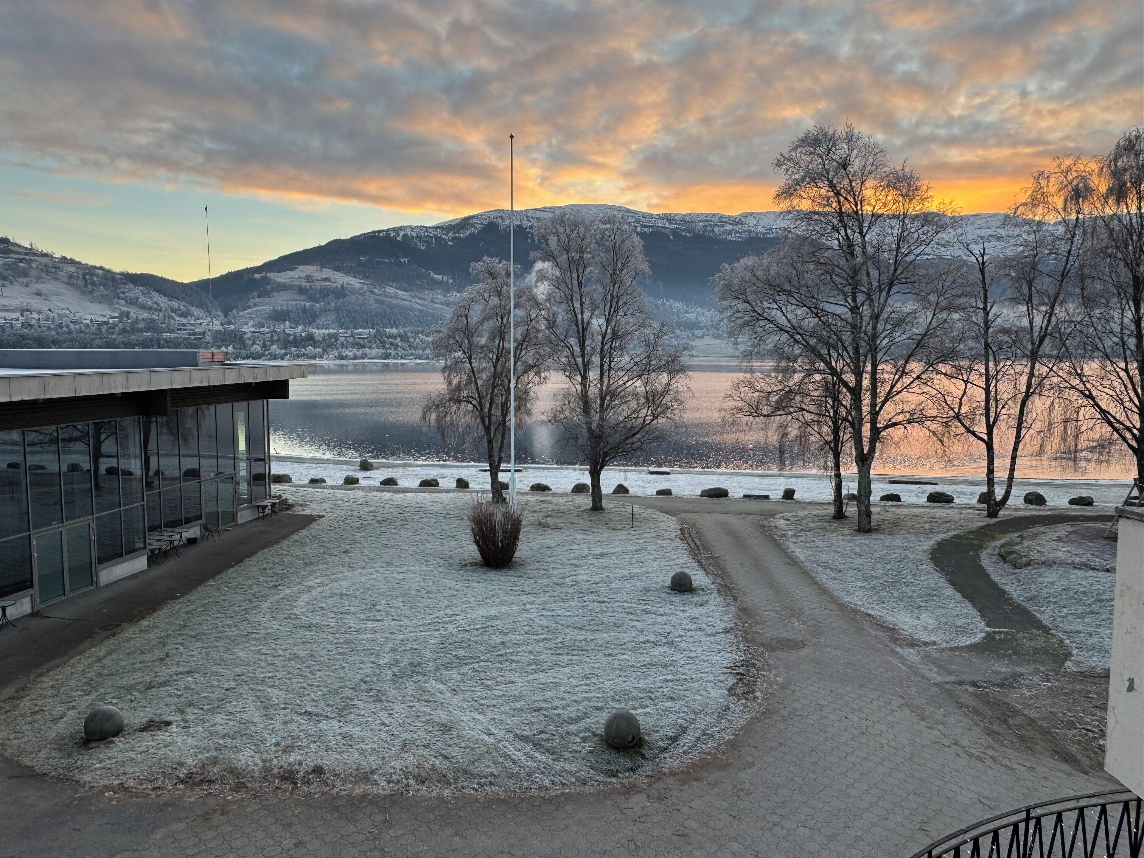 A winter scene with a building, a pathway, and a lake.