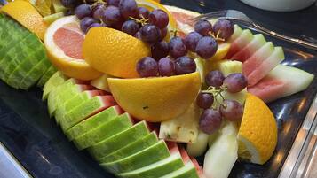 Una bandeja con frutas cortadas, como naranjas, uvas y sandía.