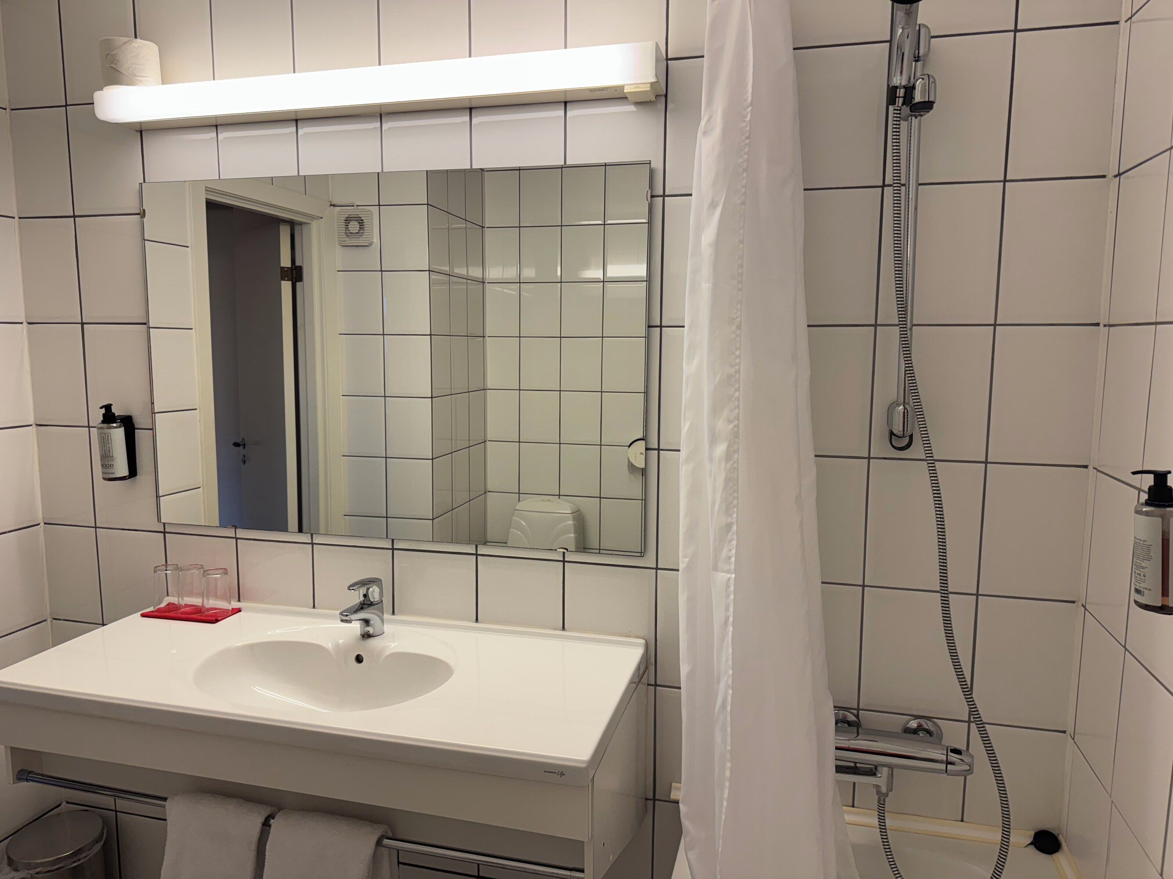 A bathroom with a white sink, mirror, and shower.