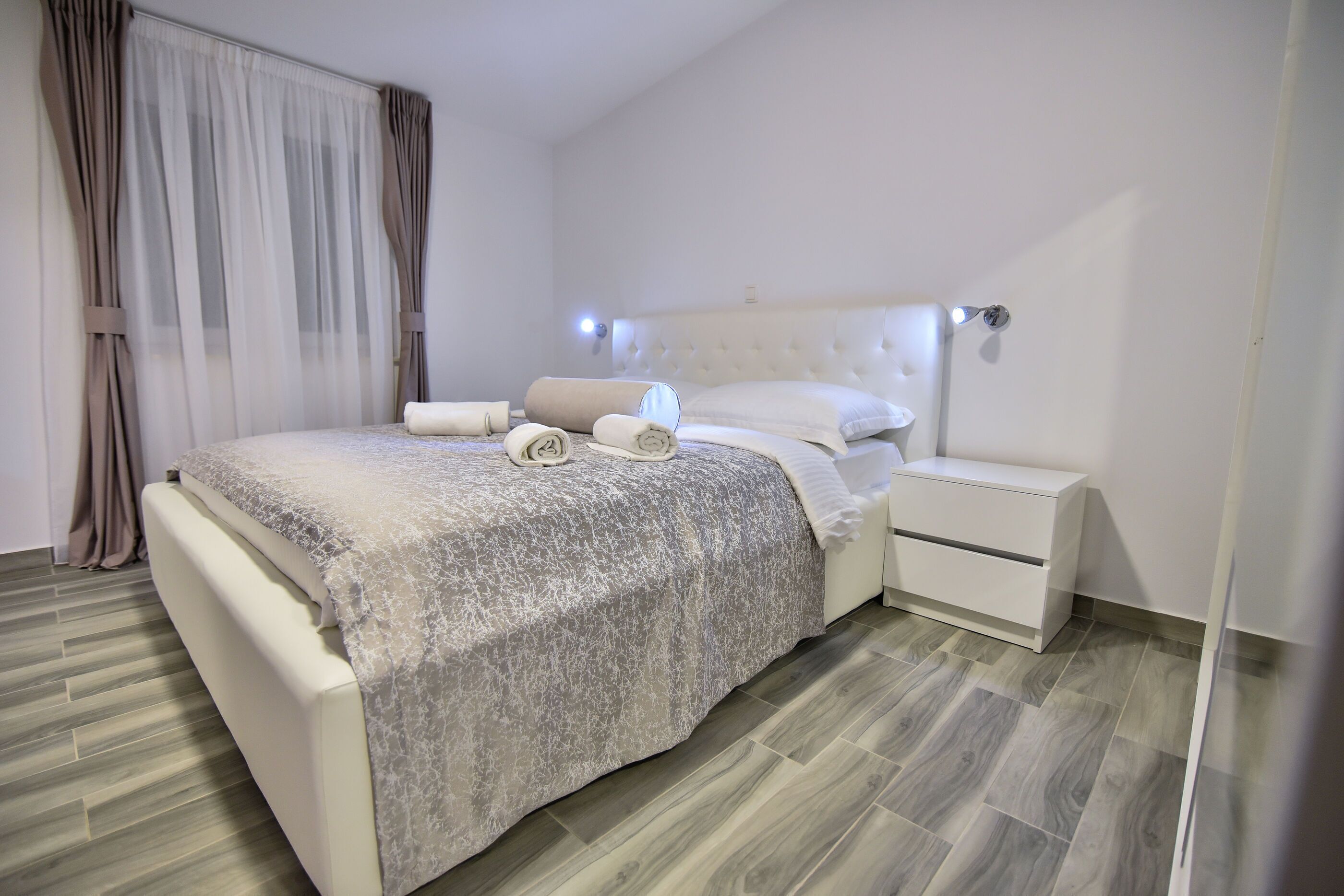 Une chambre moderne avec un grand lit, une table de chevet et une commode.