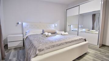 Un dormitorio moderno con una cama grande, una mesita de noche, un armario y un espejo.