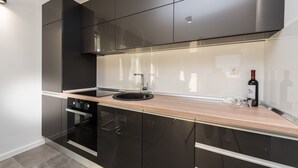 A modern kitchen with black cabinets, a wooden countertop, and a stainless steel sink. - Villa Magnifica Penthouse with Jacuzzi (Novalja)