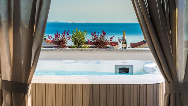 A hot tub with a view of the sea, a bottle, and some plants. - Villa Magnifica Penthouse with Jacuzzi (Novalja)