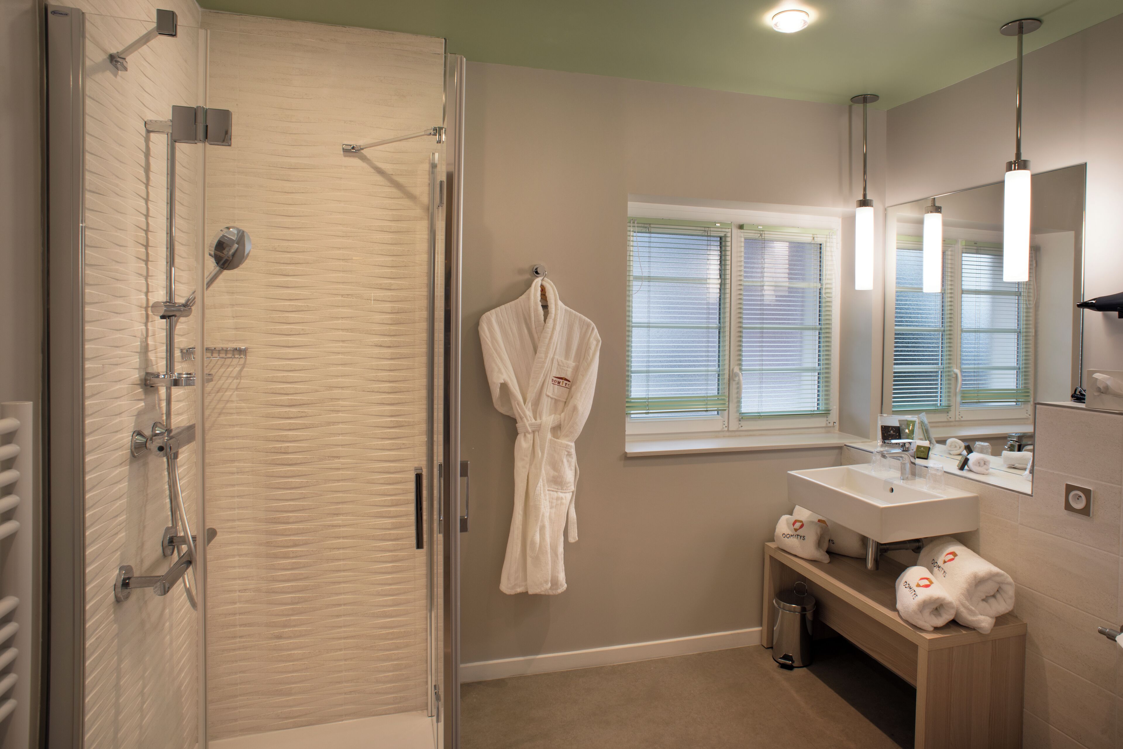 Une salle de bain avec une douche à parois de verre, un lavabo blanc, un miroir et un porte-serviettes.