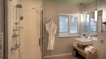 Une salle de bain avec une douche à parois de verre, un lavabo blanc, un miroir et un porte-serviettes.