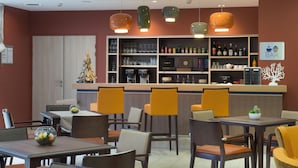 A restaurant with multiple tables and chairs, a bar area, and shelves stocked with bottles and glasses. - Manoir Le Carillon dOr (Maubeuge)
