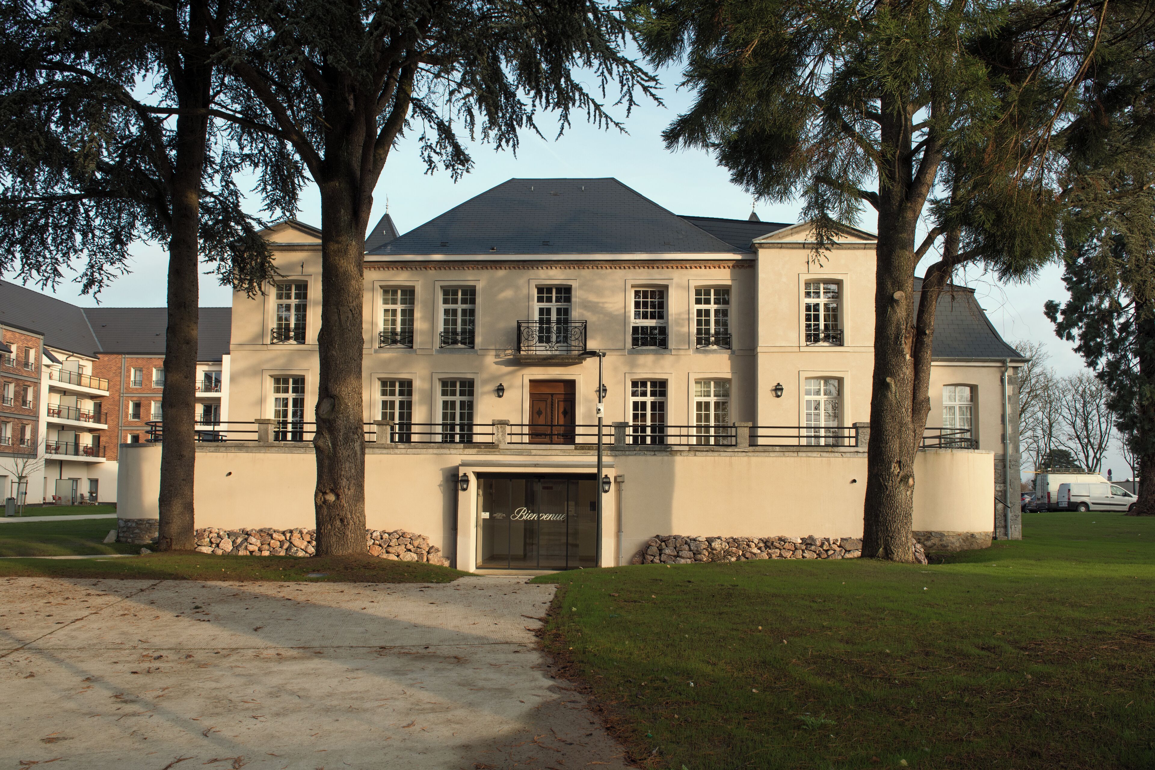 A large, multi-story building with a symmetrical facade, a central entrance, and a stone foundation.