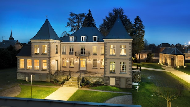 A large, two-story building with a symmetrical facade, multiple windows, and a central entrance with steps leading up to it. - Manoir Le Carillon dOr (Maubeuge)