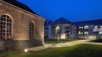 A building with a stone facade, large arched windows, and a flat roof.