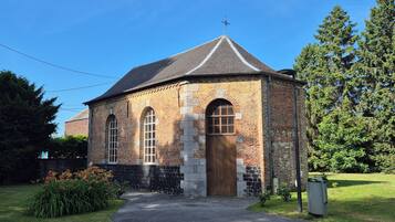 A small brick building with a pitched roof, a cross on top, and a single entrance.