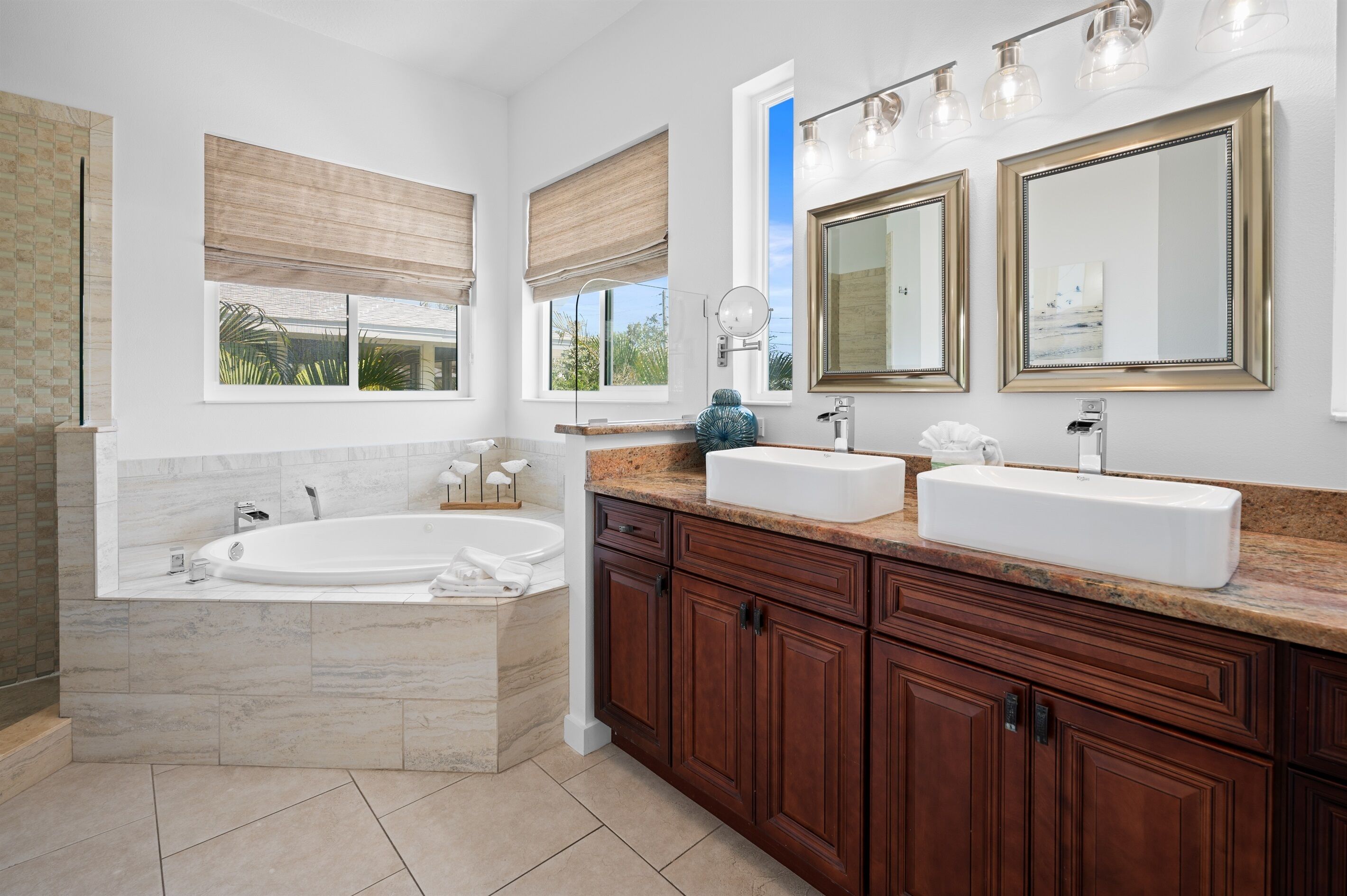 A modern bathroom with a freestanding bathtub, two sinks, and large mirrors.