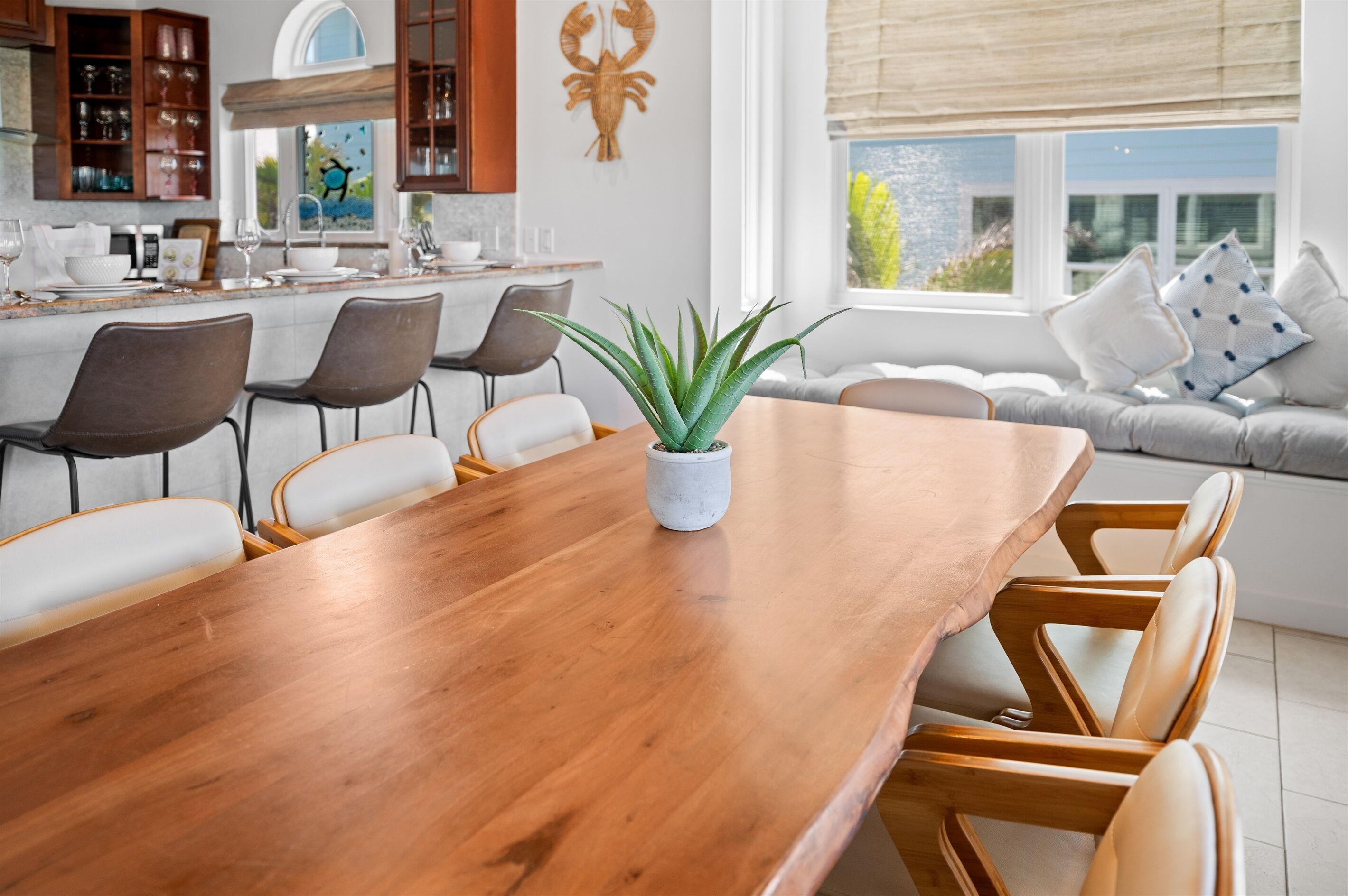 Een moderne keuken met houten kastjes, een eettafel met stoelen en een groot raam met uitzicht op groen.