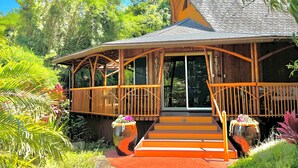 Una casa de madera con un porche, rodeada de abundante vegetación.