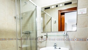 A bathroom with a glass shower enclosure, a sink, and two toilets. - Marbella Village | Patio View Terrace (Marbella)