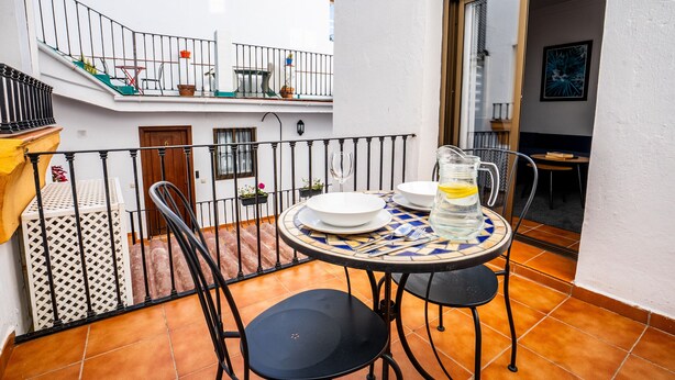 A small outdoor dining area with a round table, two chairs, and a pitcher of water. - Marbella Village | Patio View Terrace (Marbella)